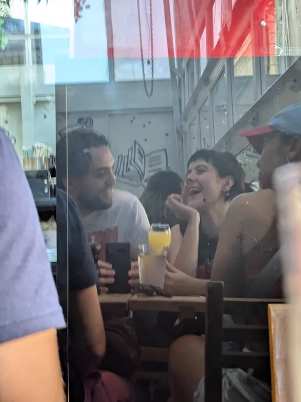 Jacob and Vicki talking over drinks, seen through a restaurant window